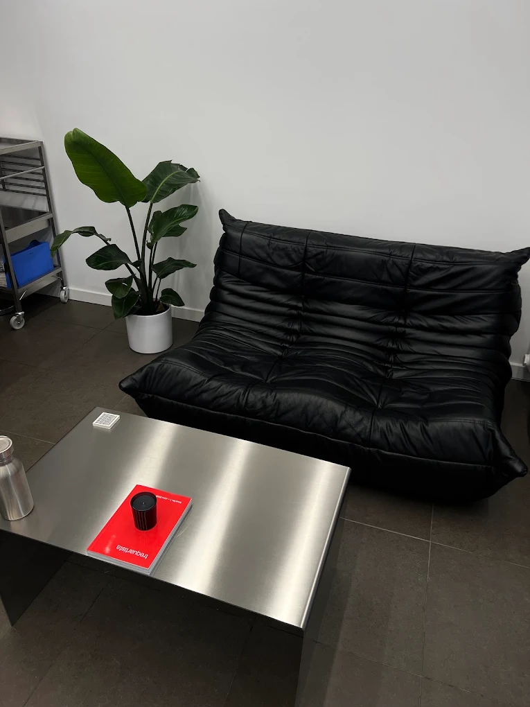 Väntyta med svart lädersoffa och stålbord hos Studio Asoi