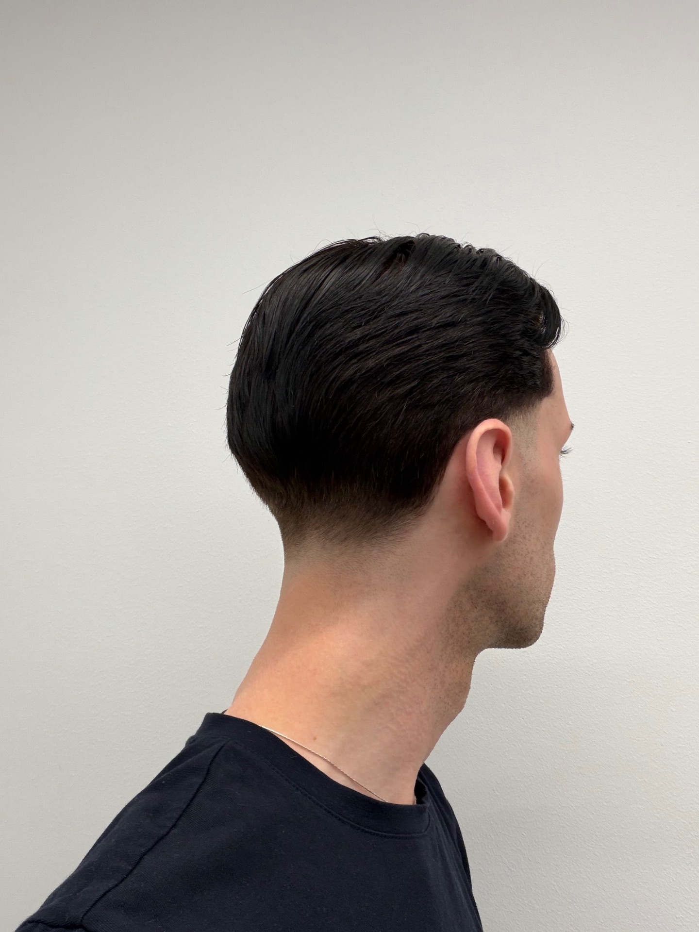 Mörk slick back med low taper fade - herrklippning Stockholm